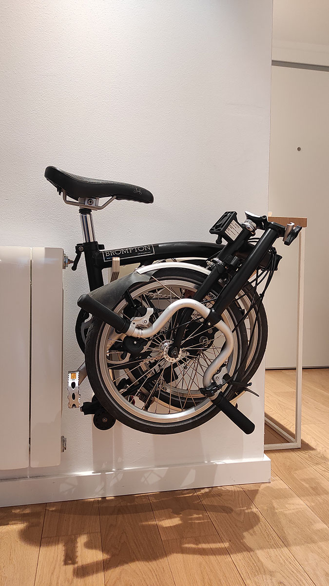 Bicicleta plegable Brompton colgada en la pared. Soporte